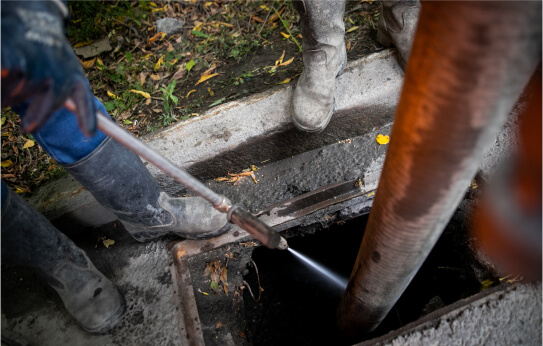 Technicians using hydro jetting tools in a dug out area.